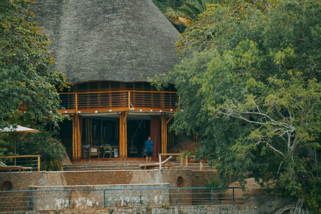 Uganda's Great Birding Arc A beautiful rustic lodge with a thatched roof nestled among lush green trees.