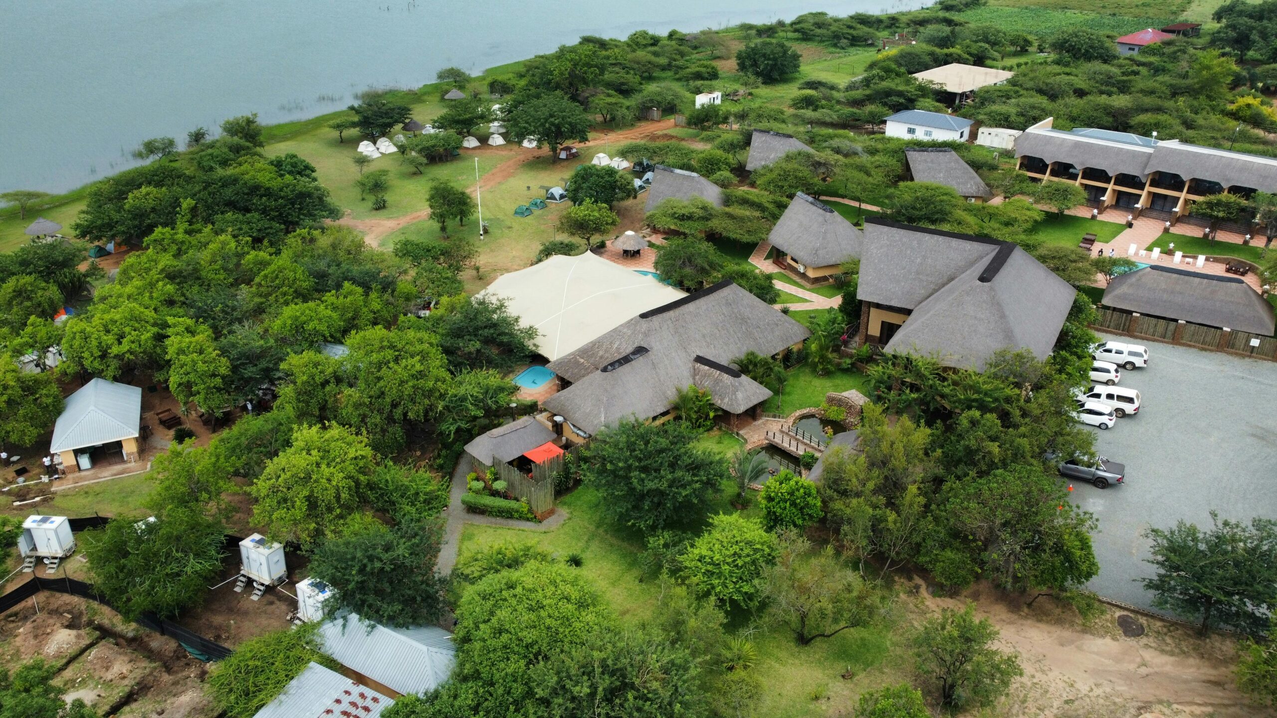 Uganda's Great Birding Arc A beautiful aerial shot of a picturesque eco lodge surrounded by lush greenery and water.